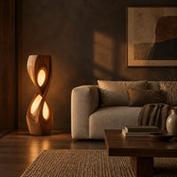 Tall twisted floor lamp with two teardrop openings that glow in a dark living room at golden hour