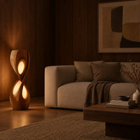 Tall twisted floor lamp with two teardrop openings that glow in an evening living room with walnut wall paneling