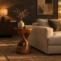 Twisted hourglass side table with a thin flat top and open waist in a dark living room at golden hour