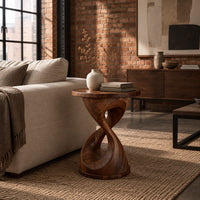 Twisted hourglass side table with a thin flat top and open waist in an industrial loft living room with exposed brick