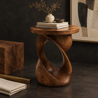 Corner detail of side table with a circular top on a twisted open loop base beside wood, brass and linen samples