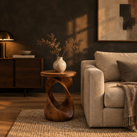 Side table with a circular top on a twisted open loop base in a dark living room at golden hour