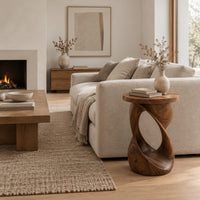 Side table with a circular top on a twisted open loop base in a Scandinavian living room with white walls