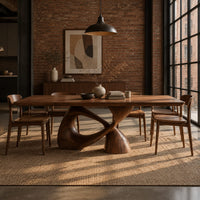 Dining table with a rectangular top on a twisted loop pedestal in an industrial loft dining room with exposed brick