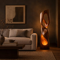 Twisted floor lamp with open loops and a glowing hollow base in a dark living room at golden hour