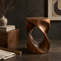 Corner detail of twisted hourglass side table with an open loop through its body beside wood, brass and linen samples