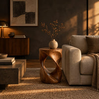 Twisted hourglass side table with an open loop through its body in a dark living room at golden hour