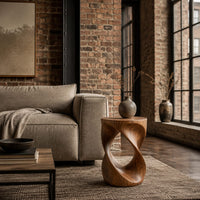 Twisted hourglass side table with an open loop through its body in an industrial loft living room with exposed brick