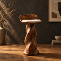 Bar stool with a twisted pedestal, a flared foot and a scooped wood seat in a dark studio against a charcoal plaster wall