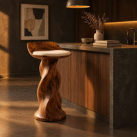 Bar stool with a twisted pedestal, a flared foot and a scooped wood seat in a dark kitchen at golden hour