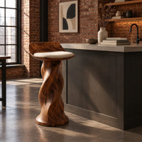 Bar stool with a twisted pedestal, a flared foot and a scooped wood seat in an industrial loft kitchen with exposed brick