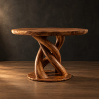 Circular wooden dining table with a twisting braided pedestal on a disc base in a dark studio against a charcoal plaster wall