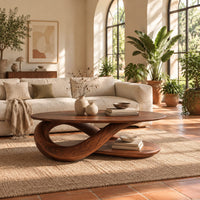 Oval coffee table on a twisted ribbon base with a flat oval shelf below in a bright living room with arched windows and plants