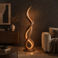 Floor lamp of twisting wooden ribbon with a glowing loop at the base in a dark living room at golden hour