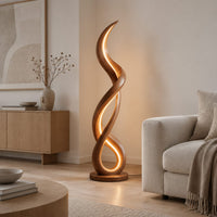 Floor lamp of twisting wooden ribbon with a glowing loop at the base in a Scandinavian living room with white walls