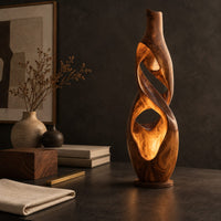Corner detail of floor lamp shaped as a twisting vase with open ribbon cutouts that glow beside wood, brass and linen samples