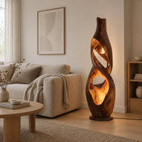 Floor lamp shaped as a twisting vase with open ribbon cutouts that glow in a Scandinavian living room with white walls