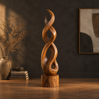 Twisted wood sculpture of intertwined ribbons on a short cylinder base in a dark studio against a charcoal plaster wall
