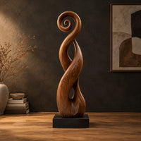 Twisted ribbon sculpture with open loops, a spiral top and a dark base in a dark studio against a charcoal plaster wall