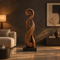 Twisted ribbon sculpture with open loops, a spiral top and a dark base in a dark living room at golden hour