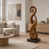 Twisted ribbon sculpture with open loops, a spiral top and a dark base in a Scandinavian living room with white walls