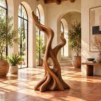 Twisted root style sculpture with an open hollow and two flame shaped tips in a bright living room with arched windows and plants