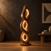 Twisted spiral floor lamp with three glowing loops on a disc base in a dark studio against a charcoal plaster wall