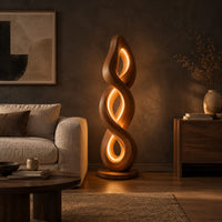 Twisted spiral floor lamp with three glowing loops on a disc base in a dark living room at golden hour