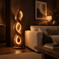 Twisted spiral floor lamp with three glowing loops on a disc base in an evening living room with walnut wall paneling
