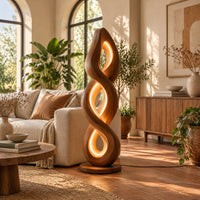 Twisted spiral floor lamp with three glowing loops on a disc base in a bright living room with arched windows and plants