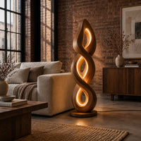 Twisted spiral floor lamp with three glowing loops on a disc base in an industrial loft living room with exposed brick