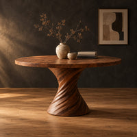 Circular dining table with a twisted spiral hourglass pedestal in a dark studio against a charcoal plaster wall