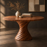 Corner detail of circular dining table with a twisted spiral hourglass pedestal beside wood, brass and linen samples