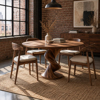 Round dining table with a twisting spiral pedestal on a circular foot in an industrial loft dining room with exposed brick