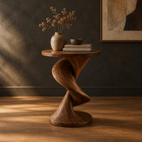 Round side table with a twisting spiral pedestal and a flared base in a dark studio against a charcoal plaster wall