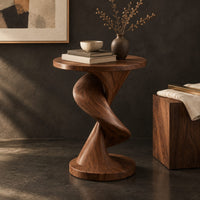 Corner detail of round side table with a twisting spiral pedestal and a flared base beside wood, brass and linen samples