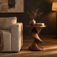 Round side table with a twisting spiral pedestal and a flared base in a dark living room at golden hour