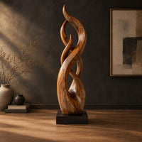 Twisting flame shaped sculpture with braided open loops on a square block base in a dark studio against a charcoal plaster wall