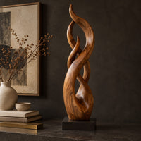 Corner detail of twisting flame shaped sculpture with braided open loops on a square block base beside wood, brass and linen samples