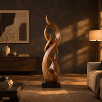 Twisting flame shaped sculpture with braided open loops on a square block base in a dark living room at golden hour