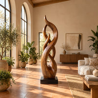 Twisting flame shaped sculpture with braided open loops on a square block base in a bright living room with arched windows and plants