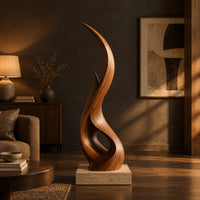 Tall twisting flame shaped wood sculpture with an open loop near the base in a dark living room at golden hour