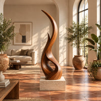 Tall twisting flame shaped wood sculpture with an open loop near the base in a bright living room with arched windows and plants