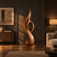 Tall twisting flame sculpture with an open loop on a flat disc base in a dark living room at golden hour