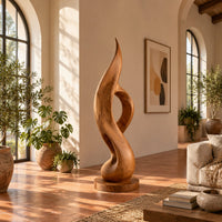 Tall twisting flame sculpture with an open loop on a flat disc base in a bright living room with arched windows and plants