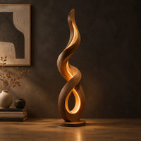 Twisting ribbon floor lamp with warm glow inside its loops in a dark studio against a charcoal plaster wall
