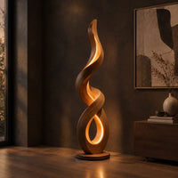 Twisting ribbon floor lamp with warm glow inside its loops, three-quarter view showing the grain