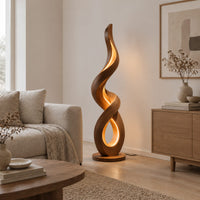 Twisting ribbon floor lamp with warm glow inside its loops in a Scandinavian living room with white walls