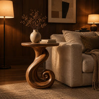 Round side table on a ribbon pedestal that ends in a spiral curl in an evening living room with walnut wall paneling