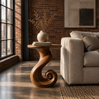 Round side table on a ribbon pedestal that ends in a spiral curl in an industrial loft living room with exposed brick